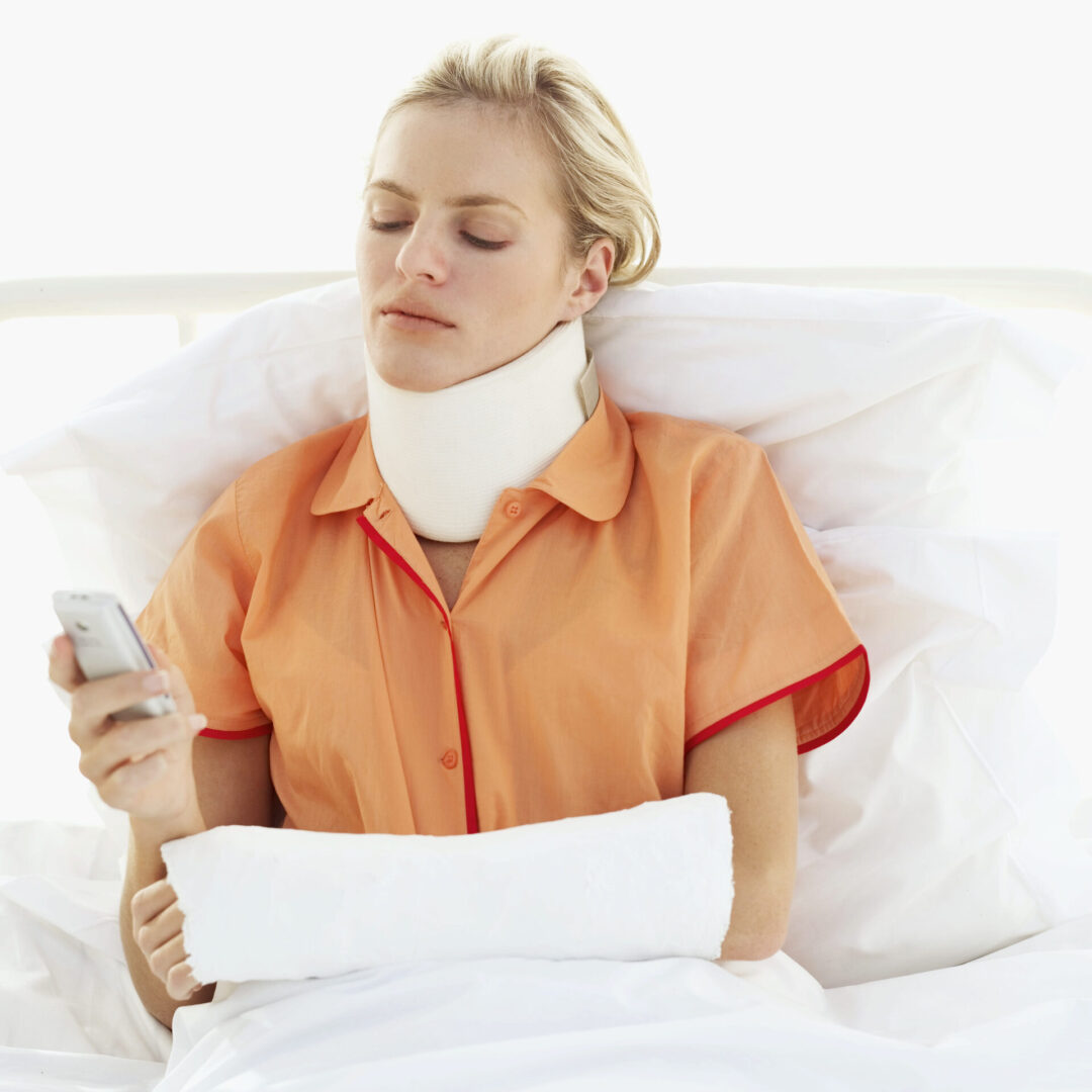 female patient lying on a bed operating a mobile phone